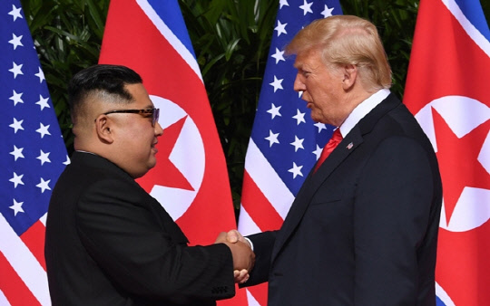 작년 6월12일 싱가포르에서 열린 북-미 정상회담에서 김정은 북한 국무위원장과 도널드 트럼프 미국 대통령이 악수하고 있다. <연합 제공>